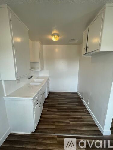 A kitchen with white cabinets and a wooden floor.