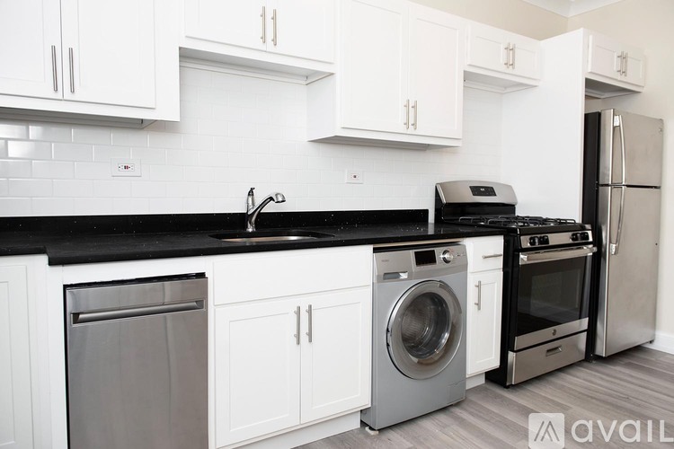 A kitchen with white cabinets and black countertops.