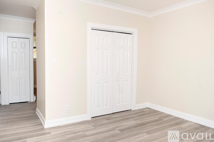 A room with a white door and wooden flooring.