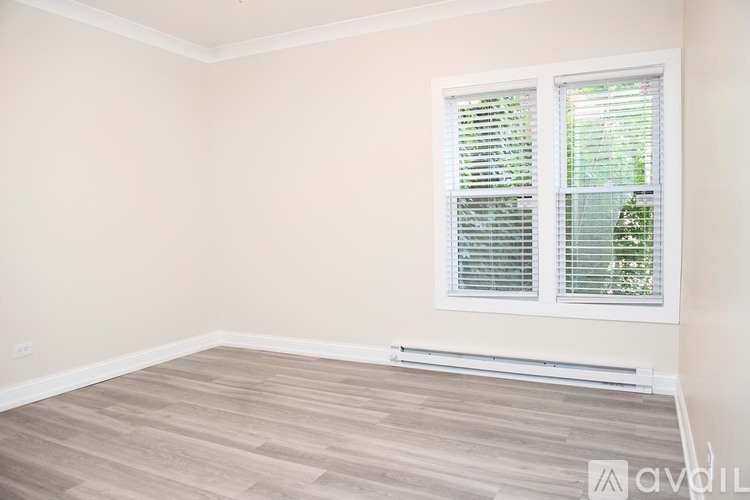 A room with a window covered by white blinds.