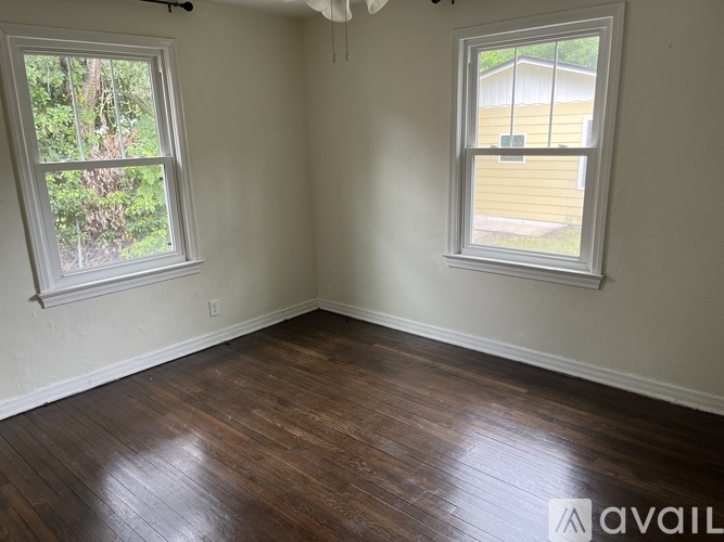 A room with two windows and wooden flooring.
