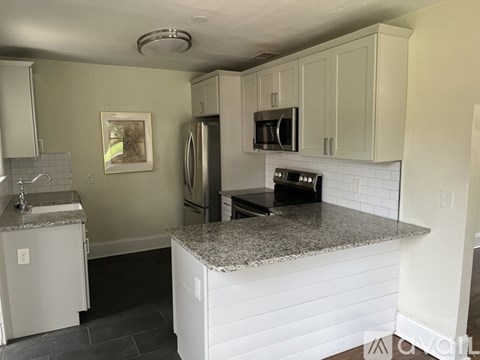 A kitchen with a granite countertop and white cabinets.