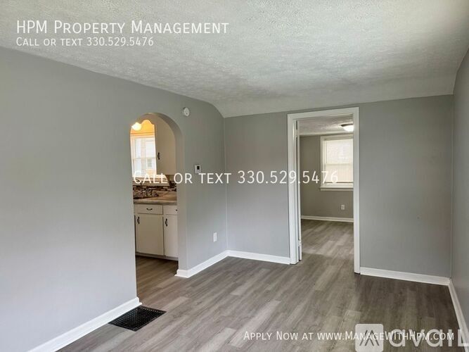 A room with a doorway leading to another room, and a sign for HPM Property Management with a phone number.