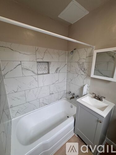A bathroom with a marble tile wall and a white bathtub.