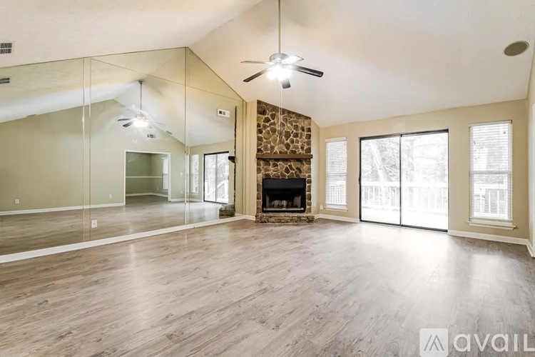 A spacious room with wood flooring and a fireplace.