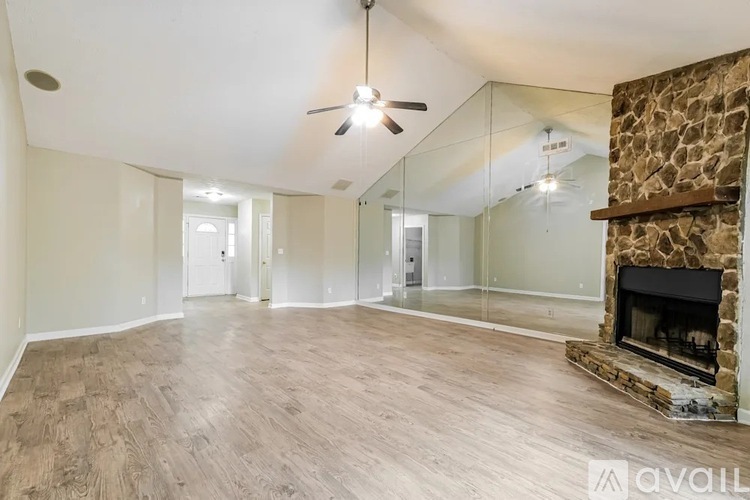 A spacious living room with a fireplace and a ceiling fan.
