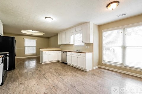 A kitchen with white cabinets and a black refrigerator.