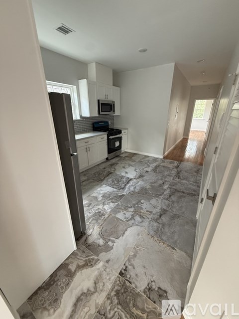 A kitchen with a marble floor and white walls.