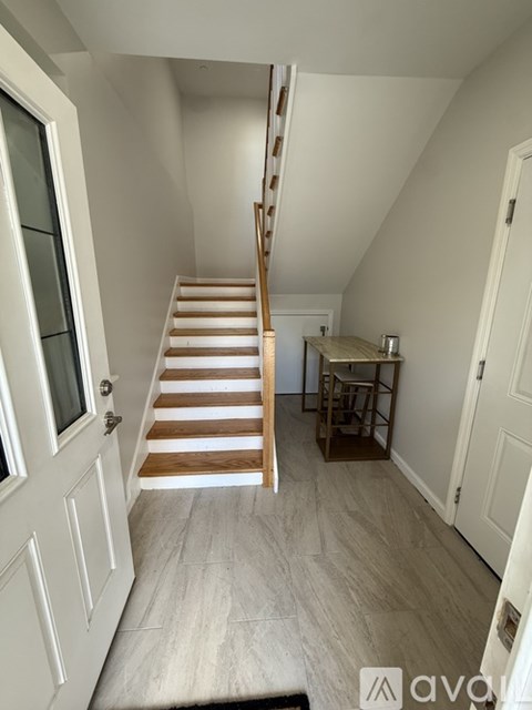 A wooden staircase leads up to a small room with a table and chairs.