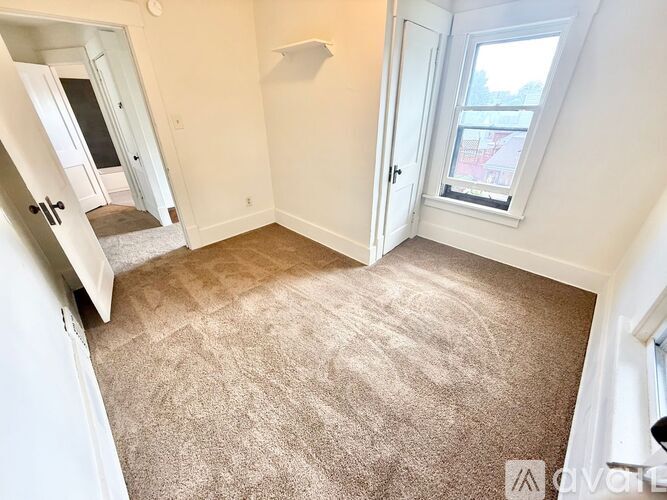 A room with a carpeted floor and a window.