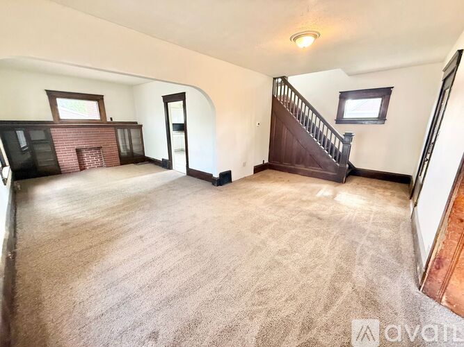 A spacious room with a carpeted floor and a staircase.
