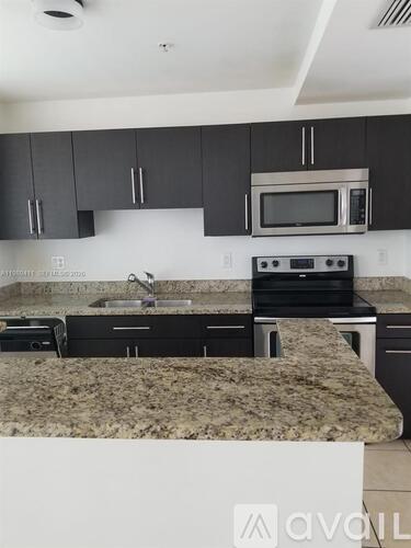 A kitchen with granite countertops and black cabinets.