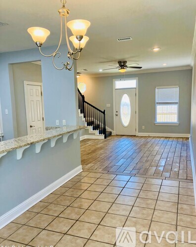 A spacious room with a chandelier, a ceiling fan, and a staircase.