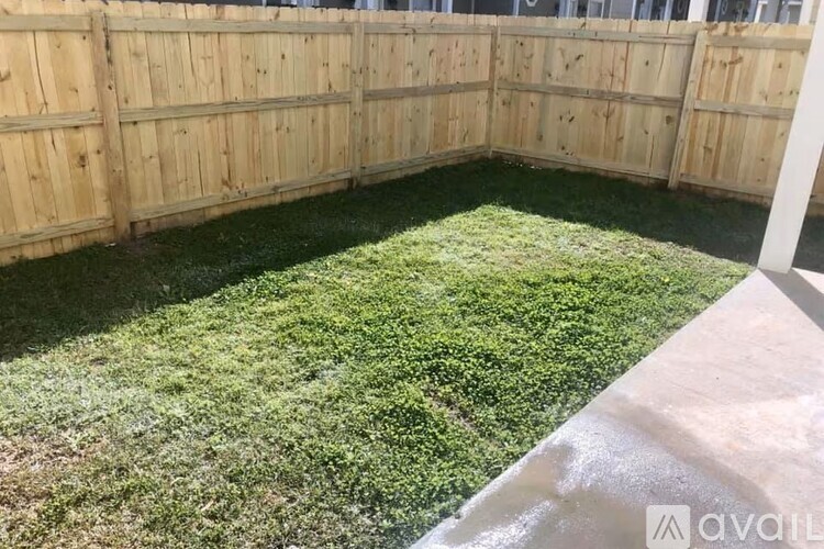 A backyard with a wooden fence and green grass.