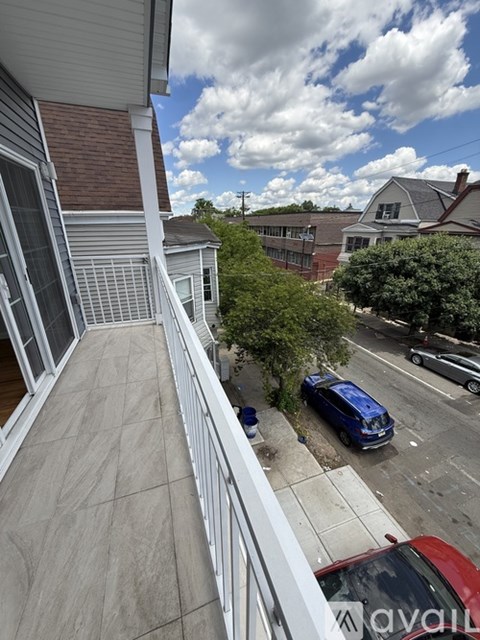 A balcony with a view of a street with cars and houses.