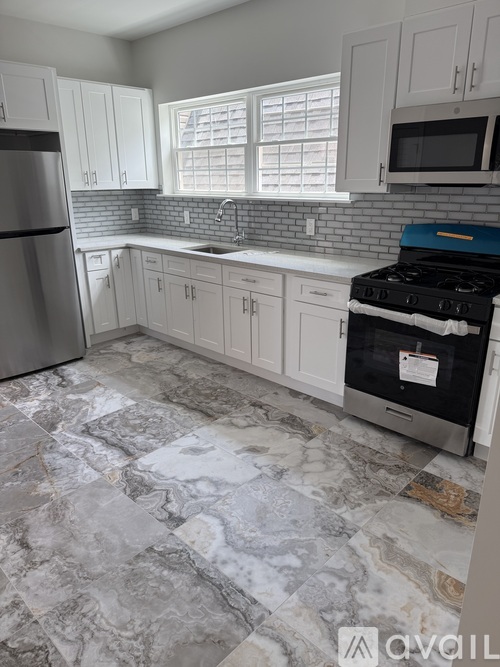 A kitchen with a black stove top oven and a marble floor.