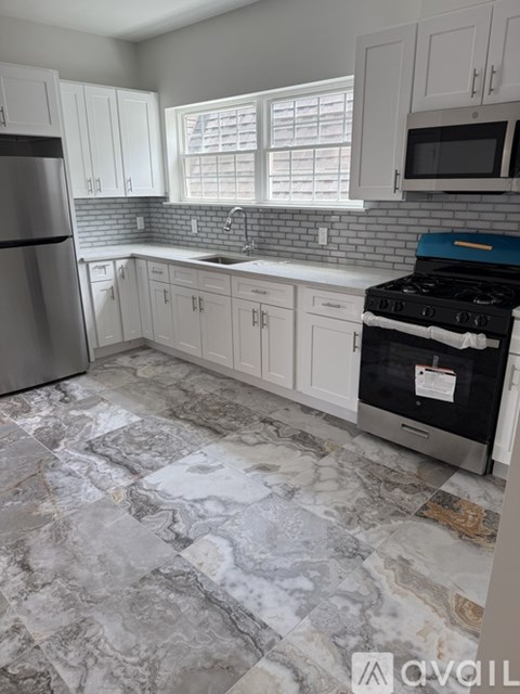 A kitchen with a black stove top oven and a marble floor.