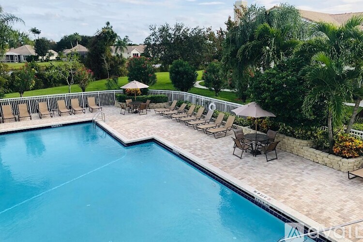 A large outdoor swimming pool surrounded by a patio with chairs and umbrellas.