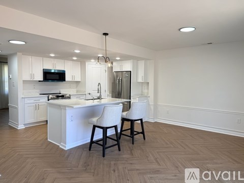 A modern kitchen with white cabinets and a wooden floor.