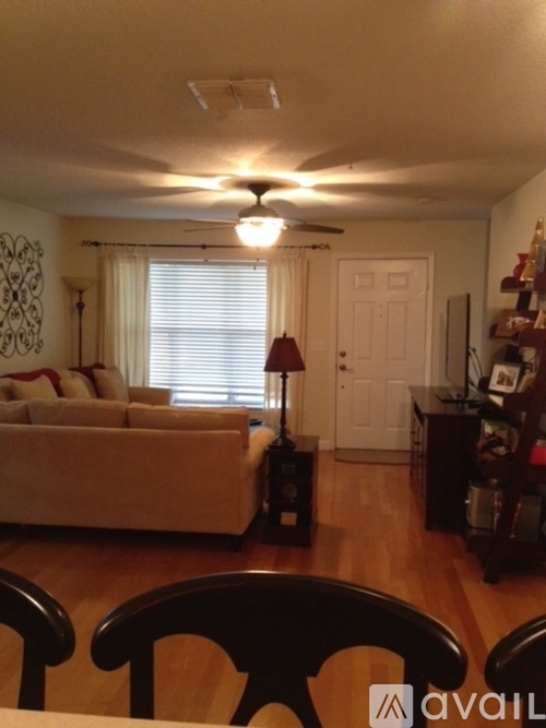 A living room with a couch, a chair, and a table with a lamp on it.