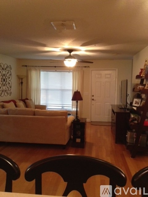 A living room with a couch, a chair, and a table with a lamp on it.