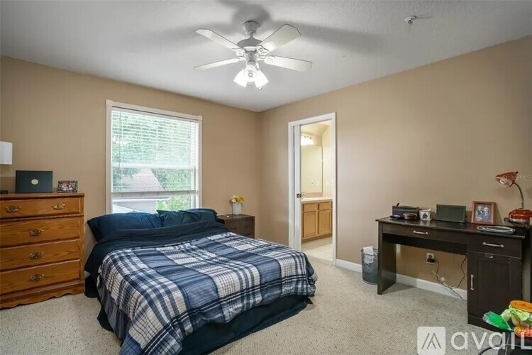 A bedroom with a bed, desk, and window.