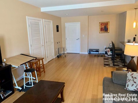 A living room with a wooden floor and a dining area with a table and chairs.