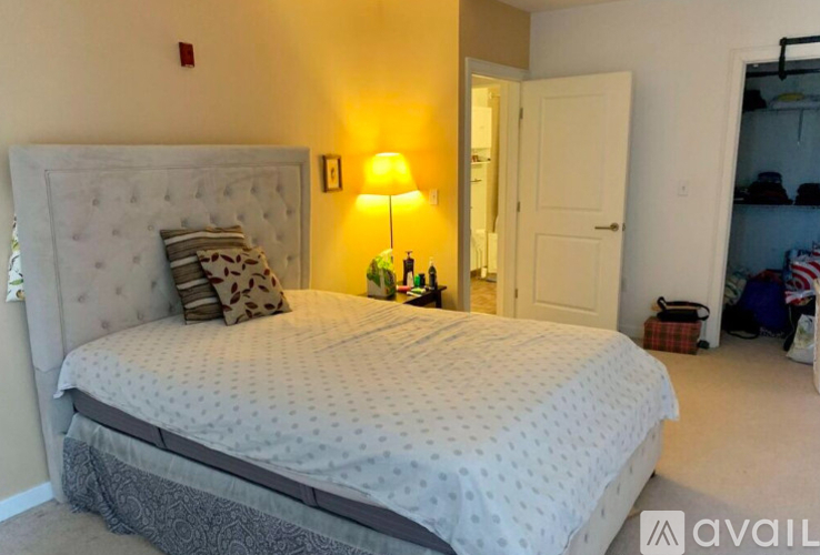 A bedroom with a large bed and a lamp on the side table.
