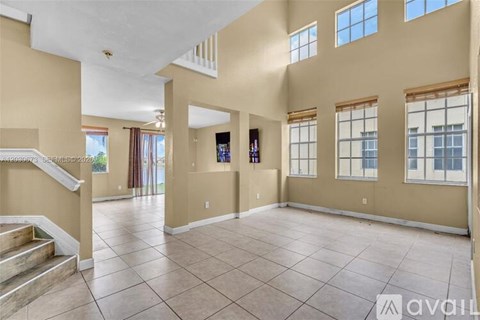 A spacious living room with beige walls and a tiled floor.