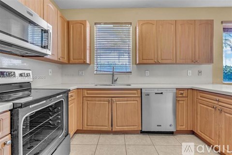 A kitchen with wooden cabinets and a stainless steel dishwasher.