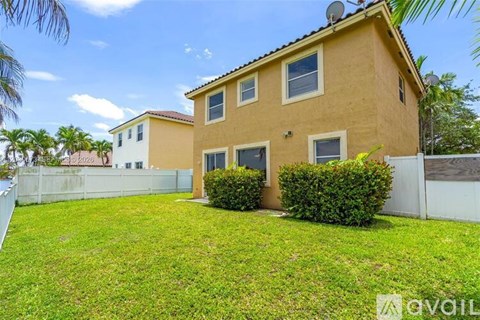 A house with a fence and green grass in front.