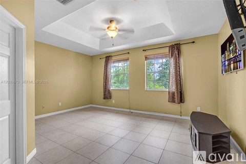 A room with a ceiling fan and a window with curtains.