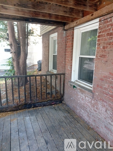 A wooden deck with a brick wall and a window.