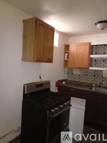 A kitchen with a black stove top oven and wooden cabinets.