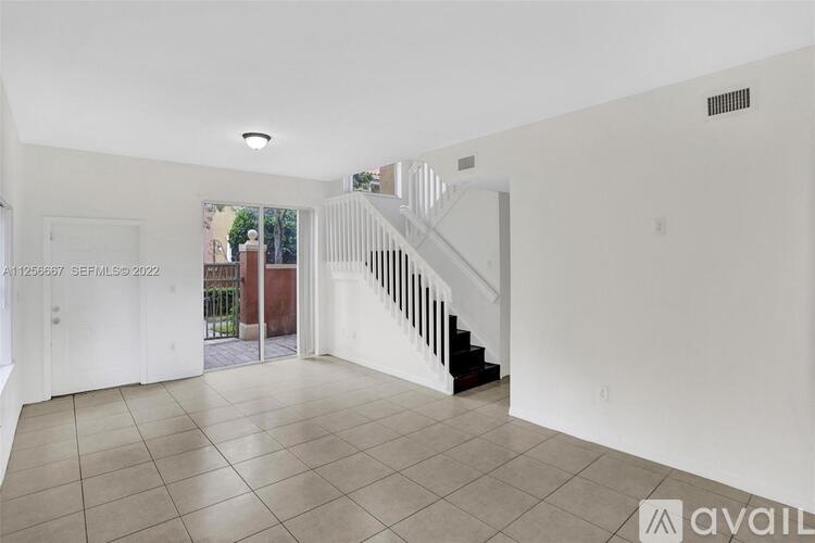A spacious, empty room with a staircase and a door leading to a balcony.