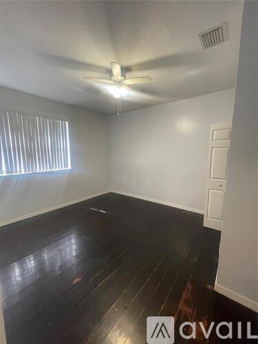 A room with a ceiling fan and wooden floors.