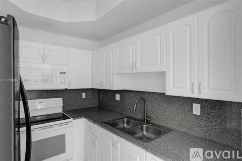 A kitchen with white cabinets and a black refrigerator.
