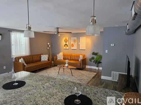 A living room with a brown sofa and a glass table.