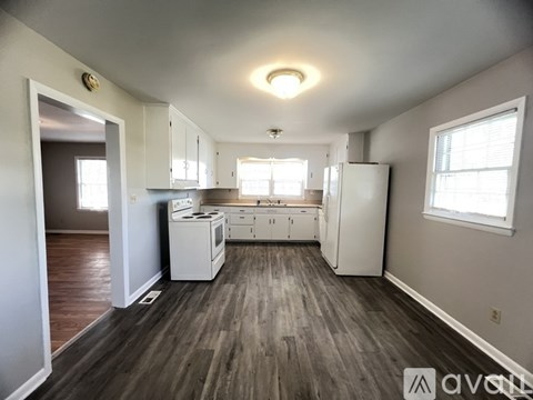 A kitchen with white appliances and wooden floors.