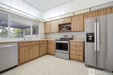 A kitchen with wooden cabinets and a stainless steel refrigerator.