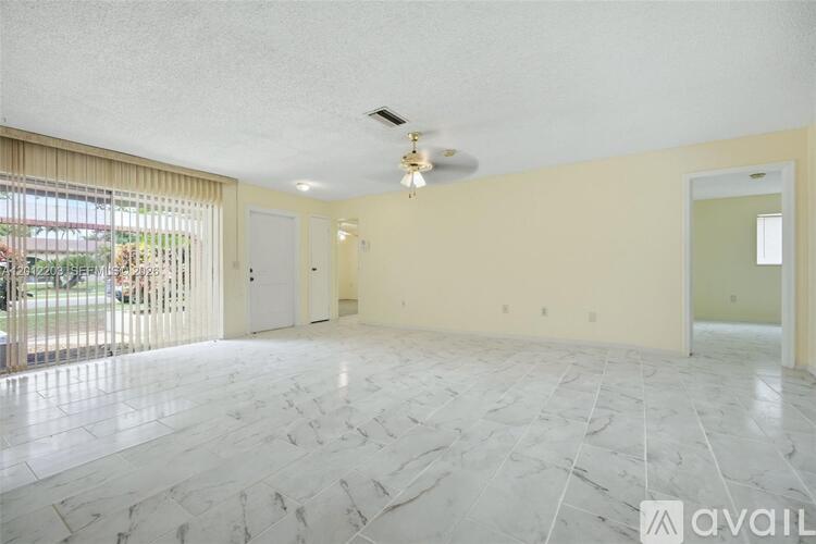 A spacious room with marble flooring and a ceiling fan.