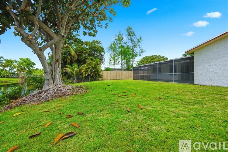 A backyard with a tree, grass, and a fence.