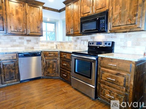A kitchen with wooden cabinets and a black microwave above the stove.