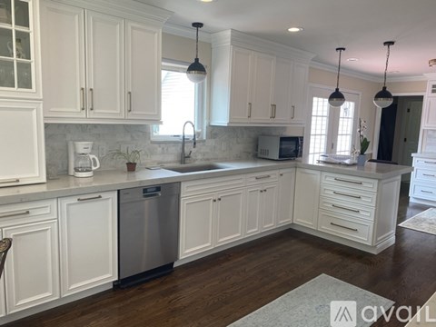 A kitchen with white cabinets and a wooden floor.
