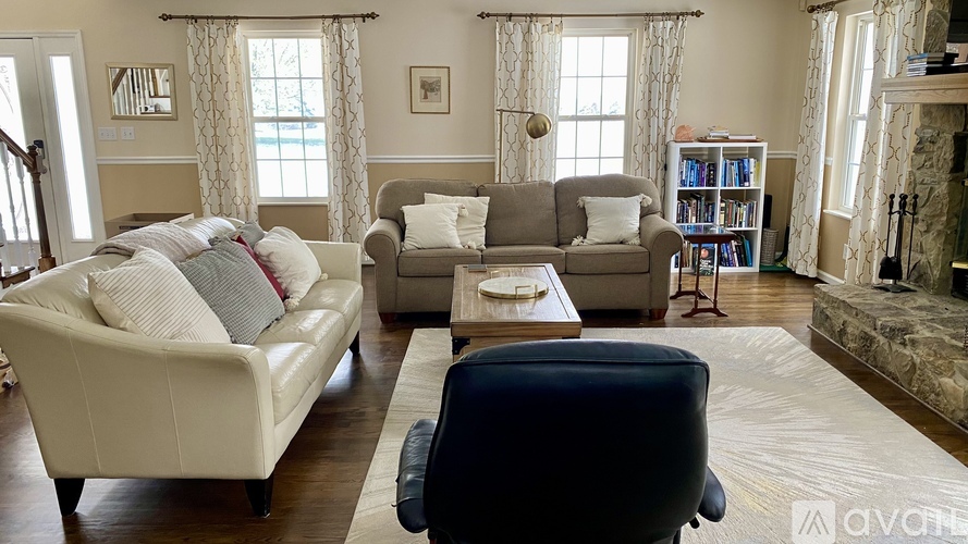 A living room with a white couch, a grey couch, a coffee table, and a fireplace.