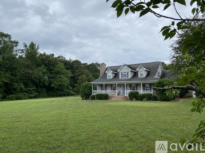 A house with a large lawn and trees in the background.