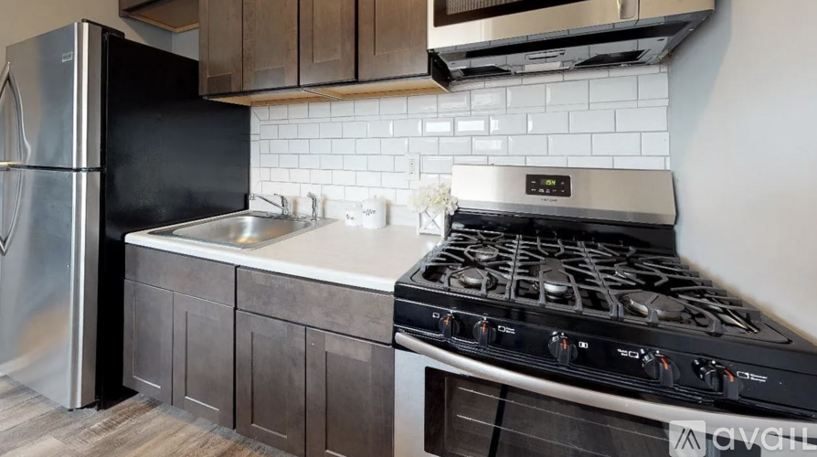 A kitchen with a stove, sink, and refrigerator.