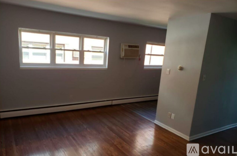 A room with wooden floors and a window with a view of a building outside.