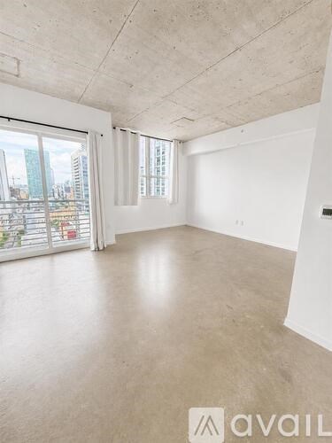 A large, empty room with a view of the city through the windows.