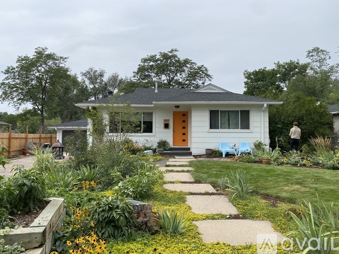 A white house with a yellow door surrounded by a garden.